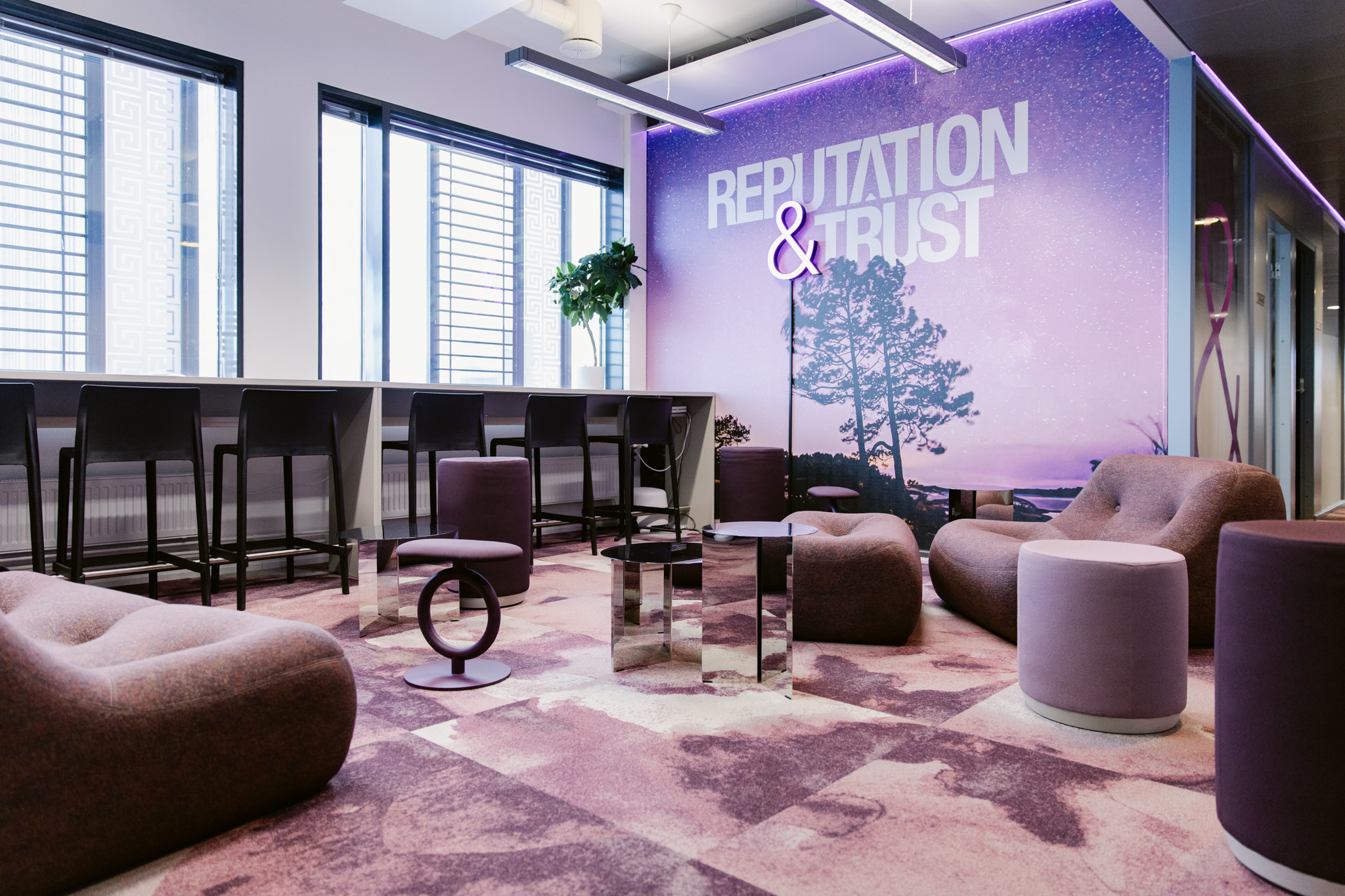 Moderni toimiston sisääntulo ja lounge-alue, jossa brändin mukaiset värit ja valaistus luovat viimeistellyn ensivaikutelman