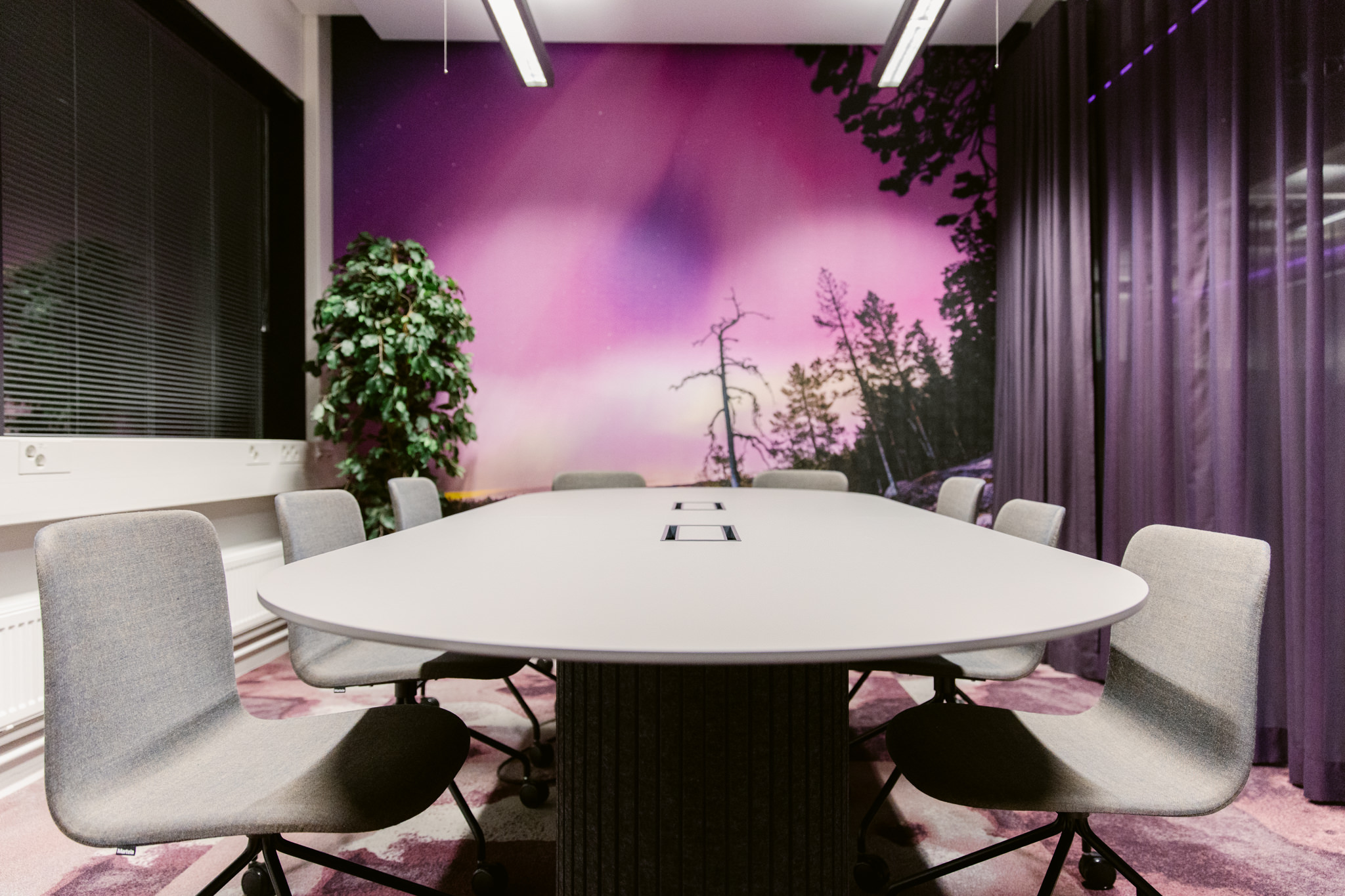 Moderni neuvottelu- ja oleskelutila, jossa lämmin valaistus ja tekstiilipinnat parantavat akustiikkaa