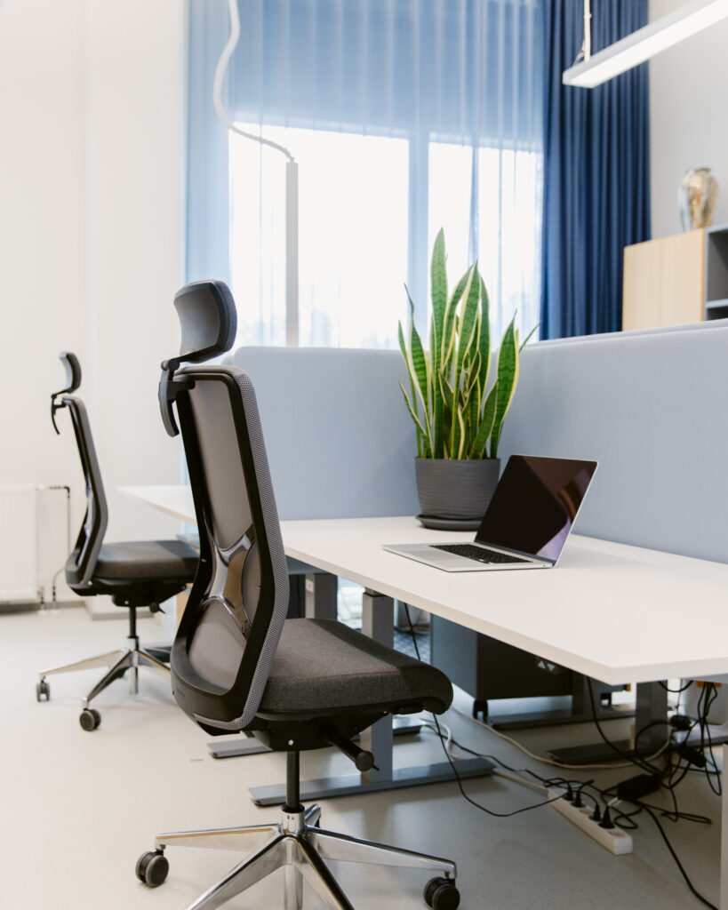 Toimiston työpiste, säädettävä pöytä Toimiston työpiste sähköpöydällä, ergonominen työtuoli ja akustoiva pöytäsermi
